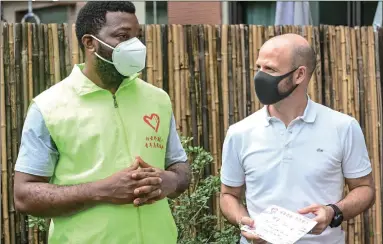  ?? Photo: cnsphoto ?? A foreign volunteer (left), who is a student at a college in Guangzhou, South China’s Guangdong Province, talks to another foreigner who lives in the city’s Baiyun district. Five volunteers in his team helped foreigners in the community during the COVID-19 pandemic.