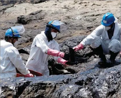  ?? CRIS BOURONCLE / AGENCE FRANCE-PRESSE ?? A cleaning crew work to remove oil from a beach in the Peruvian province of Callao on Jan 17. A spill occurred after waves caused by the volcanic eruption in Tonga moved a ship that was transferri­ng oil at a refinery.