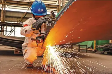  ?? — AFP ?? Fighting back: A worker welds a liquefied natural gas tank at a factory in Nantong. The State Council says the latest policies are intended to stabilise the economy and get it back onto its normal track.