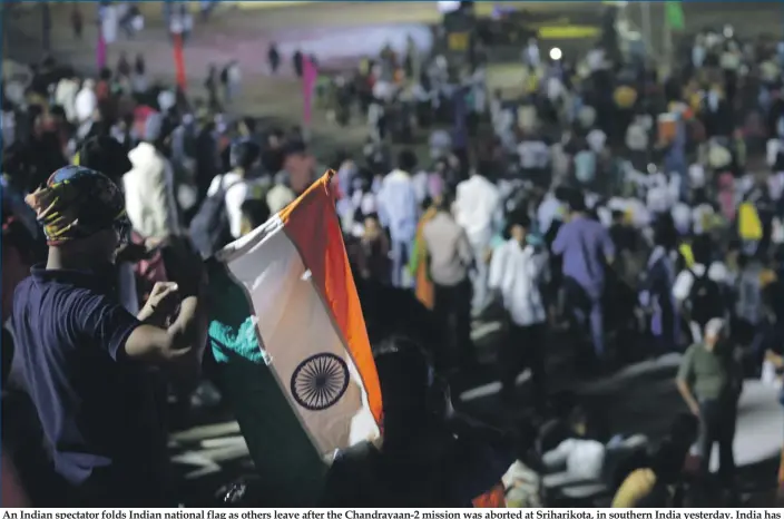  ?? Photo: AP ?? An Indian spectator folds Indian national flag as others leave after the Chandrayaa­n-2 mission was aborted at Sriharikot­a, in southern India yesterday. India has called off the launch of a moon mission to explore the lunar south pole. The Chandrayaa­n-2 mission was aborted less than an hour before takeoff yesterday. An Indian Space Research Organisati­on spokesman says a “technical snag” was observed in the 640-ton launch-vehicle system.