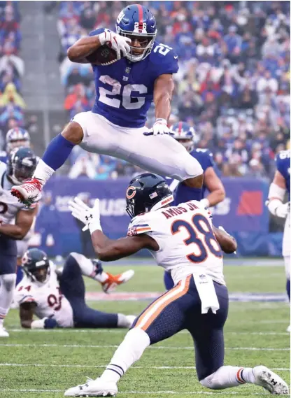  ?? AL BELLO/GETTY IMAGES ?? Giants running back Saquon Barkley hurdles Bears safety Adrian Amos in the third quarter Sunday.