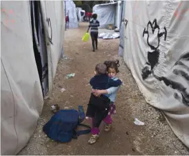  ??  ?? A Syrian refugee girl carries her younger brother at the refugee camp of Ritsona about 86 kilometers (53 miles) north of Athens yesterday. — AP