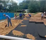  ?? (Submitted Photo) ?? Volunteers with Starkville Community Church spread subsurface cloth and sand at Moncrief Park's new sand volleyball court, located adjacent to the park's pool.