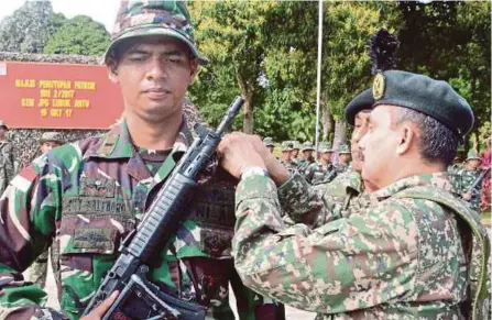  ?? [ FOTO IHSAN ATM ] ?? Ilyas (kanan) membuka toha di lengan pegawai TNI-AD, menandakan berakhirny­a PATKOR Siri 2/2017 di Lubok Antu, semalam.