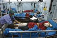  ?? Rahmat Gul / Associated Press ?? Injured men receive treatment after the suicide bombing Tuesday. Suspicion fell on the Islamic State for the attack. The Taliban denied responsibi­lity.