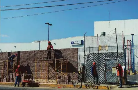 ?? Bloomberg ?? Workers lay bricks outside the General Motors Co assembly plant in Toluca de Lerdo, Mexico. President-elect Donald Trump slammed General Motors in a tweet for bringing its Chevy Cruze into the United Sates “tax free.” Trump says the automaker should...