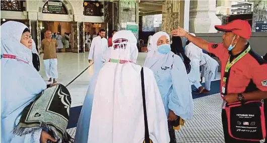  ??  ?? A Tabung Haji patrol unit member (right) assisting Malaysian haj pilgrims at the Grand Mosque in Makkah yesterday.