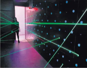  ?? Seth Wenig ?? The Associated Press Lasers fill a room that challenges visitors to pass through without touching them at SPYSCAPE, a new attraction in New York where visitors can learn about the elements of spying.