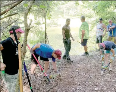  ?? Keith Bryant/The Weekly Vista ?? Volunteers clear brush and reshape the dirt to finish a spur that will connect a portion of the under-constructi­on 11 Under trails to the edge of Lake Windsor.