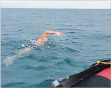  ?? MALCOLM BARTLETT ?? Tom Bartlett swims in Lake Ontario alongside a support boat on Tuesday. He pulled himself out of the water at 9:48 p.m., almost 20 hours after he started his lake crossing.