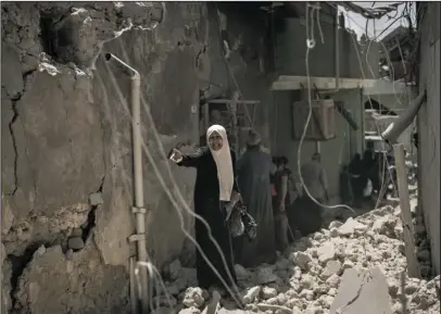  ?? The Associated Press ?? RUBBLE: An Iraqi woman flees through a destroyed alley as Iraqi Special Forces move toward Islamic State militant positions Friday in the Old City of Mosul, Iraq.