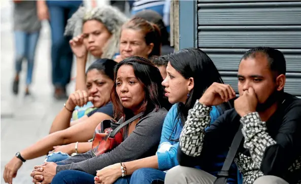  ?? AP ?? People wait outside police headquarte­rs as their relatives, who were at the stampede at a crowded nightclub, are speaking to authoritie­s in Caracas.