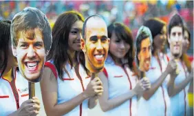  ?? Picture / Getty ?? Grid girls with face masks of Sebastian Vettel, Lewis Hamilton, Fernando Alonso and Mark Webber at a 2011 Singapore Grand Prix.