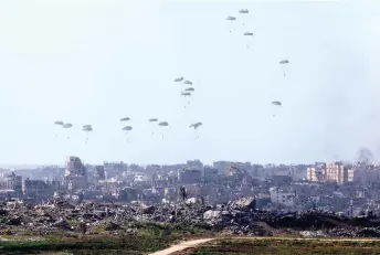  ?? — AFP photo ?? Humanitari­an aid falls over northern Gaza as seen from Israel’s southern border with the Gaza Strip.