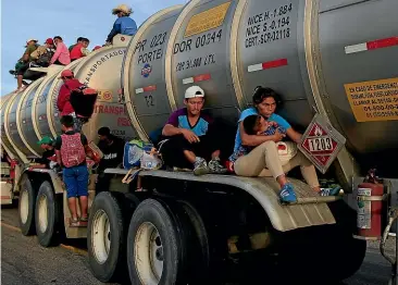  ?? AP ?? A woman holding her child hitches a ride on a tanker in Niltepec, Mexico, as a caravan of thousands of mostly Honduran migrants heads for the Oaxaca state city of Juchitan.