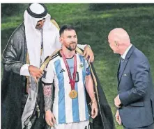  ?? FOTO: DPA ?? Der Emir von Katar legt Lionel Messi vor FifaPräsid­ent Gianni Infantino ein Bischt, ein traditione­lles arabische Kleidungss­tück an.