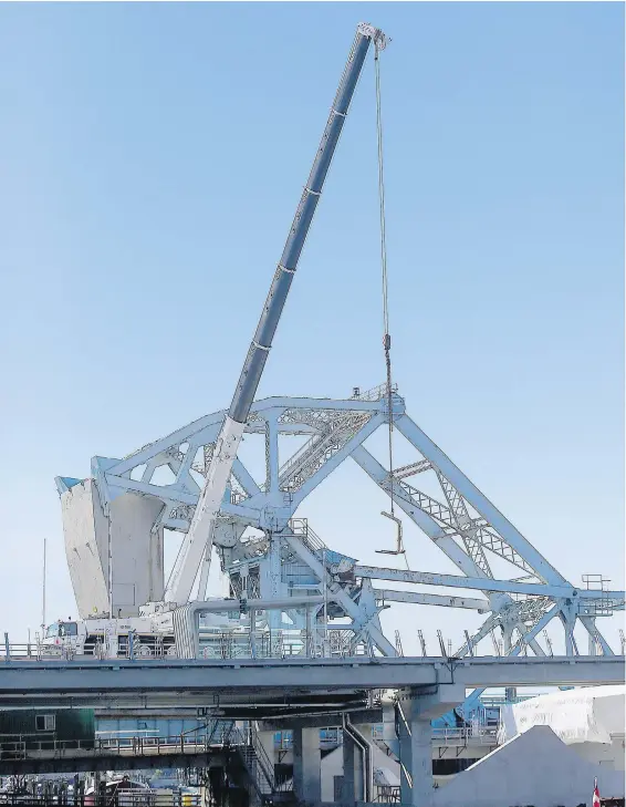  ??  ?? A segment of the new Johnson Street Bridge is raised into place with the original Blue Bridge in the background. The new bridge is scheduled to open in March 2018.