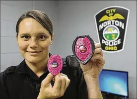  ?? PHIL MASTUROZO / BEACON JOURNAL ?? Norton police officer Heather Bauer shows off the pink-coated badges the department is wearing for Breast Cancer Awareness Month.
