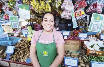  ?? ?? Iloilo Terminal Market vegetable stall owner Jasmin Marasigan now accepts cashless payments via QR code powered by LANDBANK.