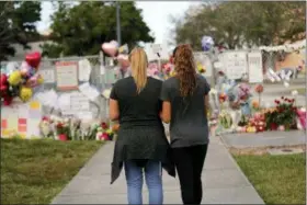  ?? ASSOCIATED PRESS FILE PHOTO ?? In this Feb. 19, 2018, file photo Sara Smith, left, and her daughter Karina Smith visit a makeshift memorial outside the Marjory Stoneman Douglas High School, where 17 students and faculty were killed in a mass shooting in Parkland, Fla.