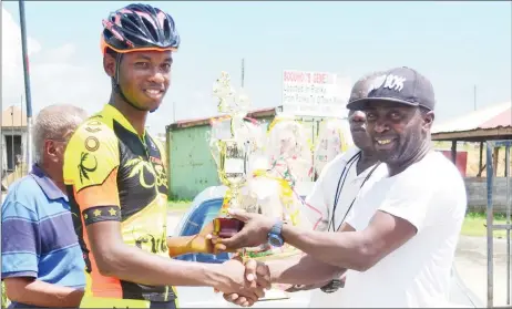  ?? (Orlando Charles photo) ?? Team Coco’s Jamal John is all smiles as he collects the winner’s spoils yesterday.