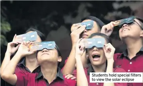  ??  ?? Students hold special filters to view the solar eclipse