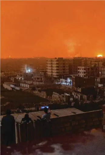  ?? Picture: AFP ?? People on a roof watch explosions in a southern district of the Syrian capital Damascus.