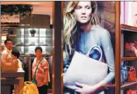  ?? YIN LIQIN / FOR CHINA DAILY ?? Chinese consumers check out luxury bags at a new duty-free shop in Shanghai on Aug 8.