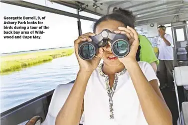  ??  ?? Georgette Burrell, 9, of Asbury Park looks for birds during a tour of the back bay area of Wildwood and Cape May.