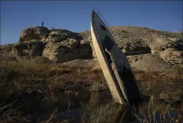  ?? JOHN LOCHER — THE ASSOCIATED PRESS ?? A formerly sunken boat sticks out of the mud Friday along the dry shoreline of Lake Mead near Boulder City, Nev.