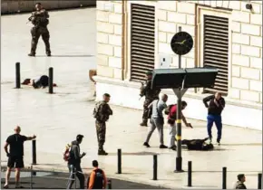  ?? PAUL-LOUIS LEGER/AFP ?? French police point a gun at a man on the ground (centre) as a stabbed woman lies (left) while soldiers secure the area following an attack on Sunday at the Saint-Charles main train station in the French city of Marseille.