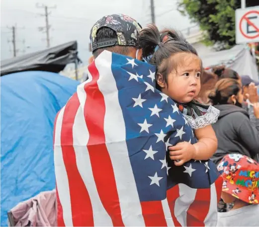  ??  ?? Inmigrante­s hondureños en Tijuana con banderas de EE.UU.