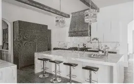  ?? Julie Soefer ?? A custom range hood and dazzliing pendant lights are focal points in this Memorial kitchen.