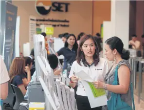  ?? PHRAKRIT JUNTAWONG ?? Workers from an asset management firm provide details about a mutual fund to customers at the Mutual Fund Fair.