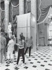  ?? DANIELLE BATTAGLIA ?? Tourists look at a box hiding the soon-to-be unveiled statue of the Rev. Billy Graham in Statuary Hall, in the Capitol, on May 11, 2024.