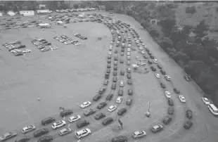  ?? Getty Images/tns ?? This aerial view shows people waiting in line in their cars at a Covid-19 testing site at Dodger Stadium in Los Angeles on Nov. 18.