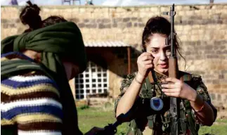  ?? AFP ?? ORMIA, a Syriac-Christian member of an all-female militia, loads her weapon at a Syrian camp near the Turkish border. The group, known as the “Female Protection Forces of the Land Between the Two Rivers,” hopes to see action against Islamic State extremists.