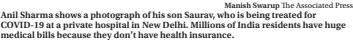  ?? Manish Swarup The Associated Press ?? Anil Sharma shows a photograph of his son Saurav, who is being treated for COVID-19 at a private hospital in New Delhi. Millions of India residents have huge medical bills because they don’t have health insurance.