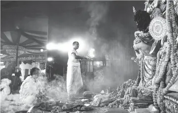  ?? — AFP photo ?? Indian Bengali Hindu priest perform ‘Arti’ ritual in front of an idol of the goddess Durga in New Delhi. The festival of Dussehra will be held on the last day of the Navratri (nine nights) Festival, symbolisin­g the triumph of good over evil, culminatin­g when firecracke­r-stuffed effigies of the demon king are set alight.