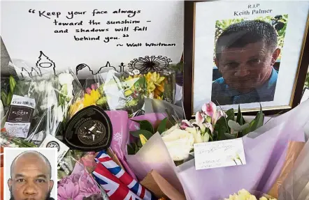  ??  ?? Fallen hero: Flowers arranged around a photograph of slain police officer Keith Palmer, one of the victims of the terror attack on Westminste­r Bridge in central London.