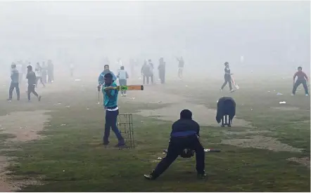  ??  ?? Pakistani youths playing cricket amid heavy pollution in Lahore. The toxic smog that has covered parts of Pakistan for weeks has exposed official torpor against rampant pollution. — AFP Dangerous games: