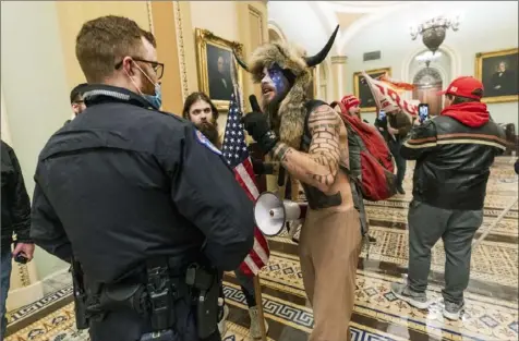  ?? Manuel Balce Ceneta/Associated Press ?? Supporters of President Donald Trump — including Jake Angeli, the conspiracy theorist nicknamed “Q Shaman,” in the horned hat — are confronted by U.S. Capitol Police officers on Jan. 6 outside the Senate Chamber inside the Capitol in Washington.