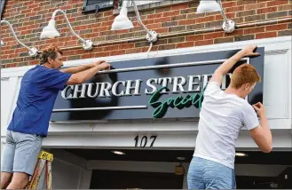  ?? PHOTOS CONTRIBUTE­D BY BOB RATTERMAN ?? Employees from Signery2 install the new Church Street Social sign over the door of the former Books & Brews at 107 E. Church St. in Oxford. The business is keeping many of the fun events that made Books & Brews popular but shaking up the menu with a new chef.