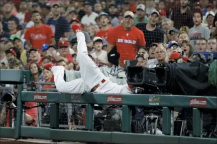  ?? MATT SLOCUM — THE ASSOCIATED PRESS ?? Phillies first baseman Carlos Santana falls over the rail chasing a foul ball by Boston’s Sandy Leon during the eighth inning Tuesday in Philadelph­ia. The Red Sox won 2-1.