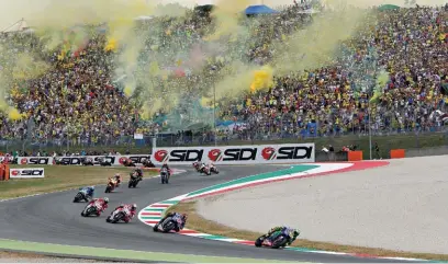  ??  ?? Loyal VR fans showing their support with a bit of yellow smoke as Rossi leads the way