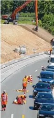  ??  ?? Bauarbeite­r markieren die Straße um, daneben staut sich der Verkehr.