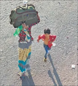  ?? REUTERS ?? Her young son in tow, a migrant worker walks in hope of catching a bus to return to their village, in Ghaziabad on Sunday.