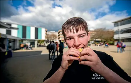  ?? DAVID UNWIN/STUFF ?? Massey University student James Pocock hooks into a mince pie during the competitio­n.