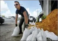  ?? GRACE BEAHM ALFORD — THE POST AND COURIER VIA AP ?? Kevin Orth loads sandbags into cars on Milford Street as he helps residents prepare for Hurricane Florence, Monday in Charleston, S.C.