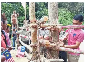  ??  ?? At an impasse: Orang asli protesters holding the Jalur Gemilang as enforcemen­t personnel dismantle one of the blockades in Gua Musang.